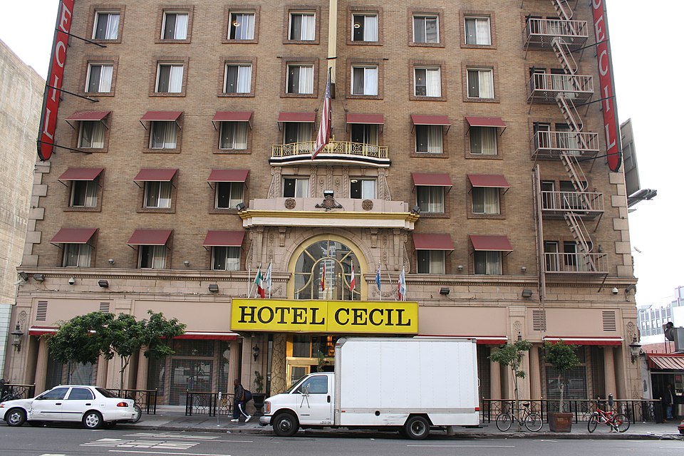 Fachada exterior del histórico Hotel Cecil (Stay on Main) en Los Ángeles de noche, conocido por su historial de muertes y actividad paranormal.