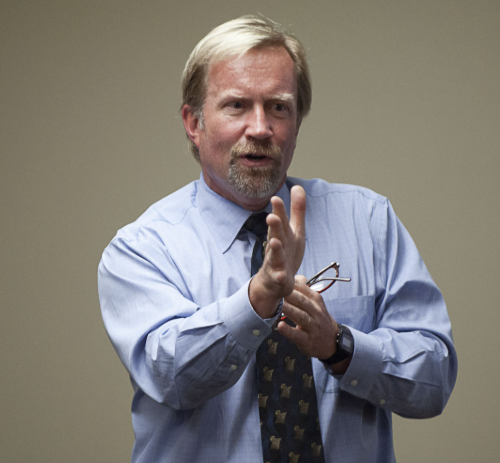 Dr. Jonathan Reed hablando y gesticulando durante una conferencia pública.