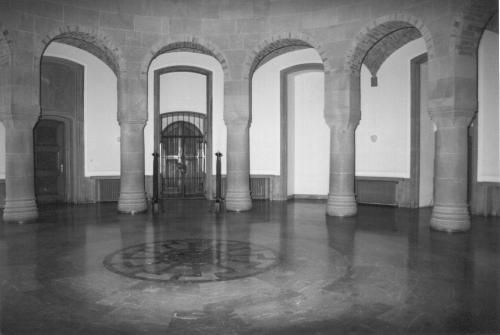 Vista interior de la sala circular del Obergruppenführersaal en el castillo de Wewelsburg, mostrando la arquitectura de bóvedas, columnas de piedra y el infame mosaico verde oscuro del Sol Negro incrustado en el centro del suelo.